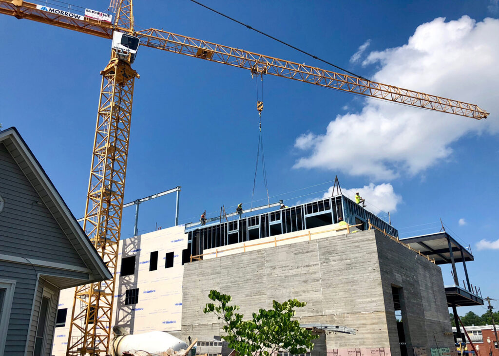 A large crane lowers a beam onto a construction site.