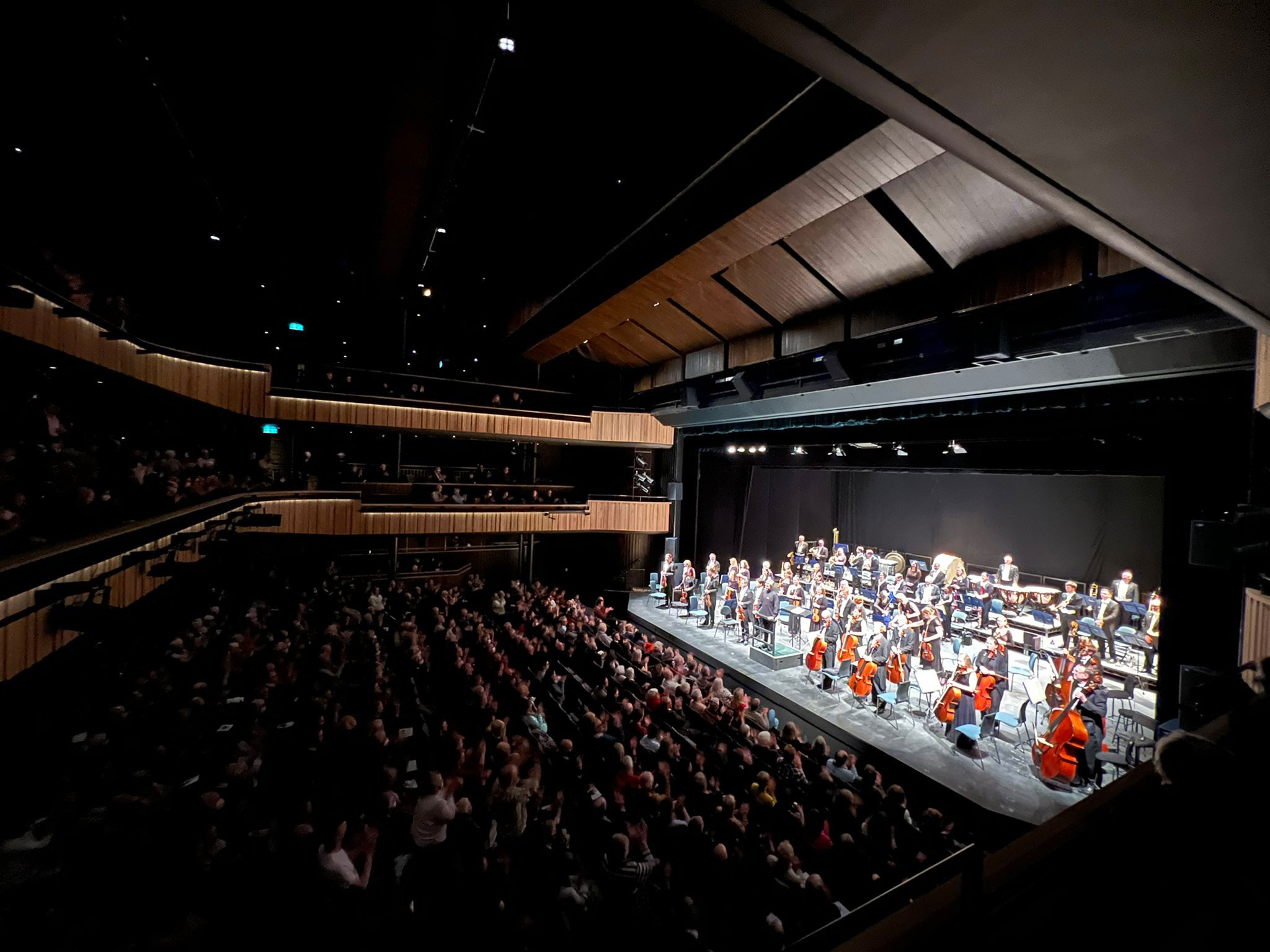 An orchestra plays while an audience watches.