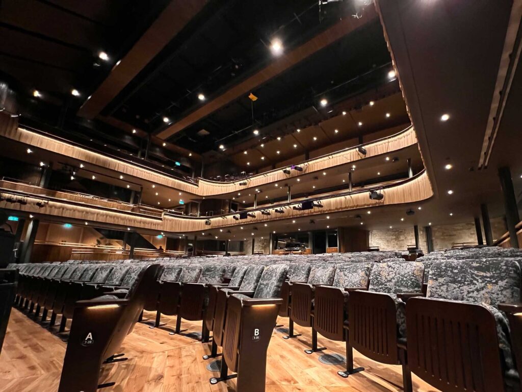View from the floor of an empty theatre showing multiple levels of seating.