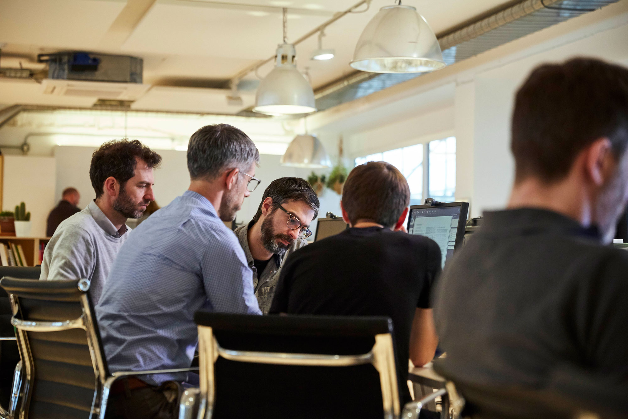 Team members circle around a computer.