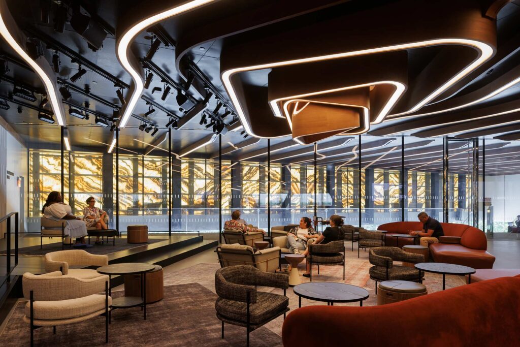 A lounge with a glowing spiral ceiling feature. The glowing marble PAC NYC facade fills the rear wall.