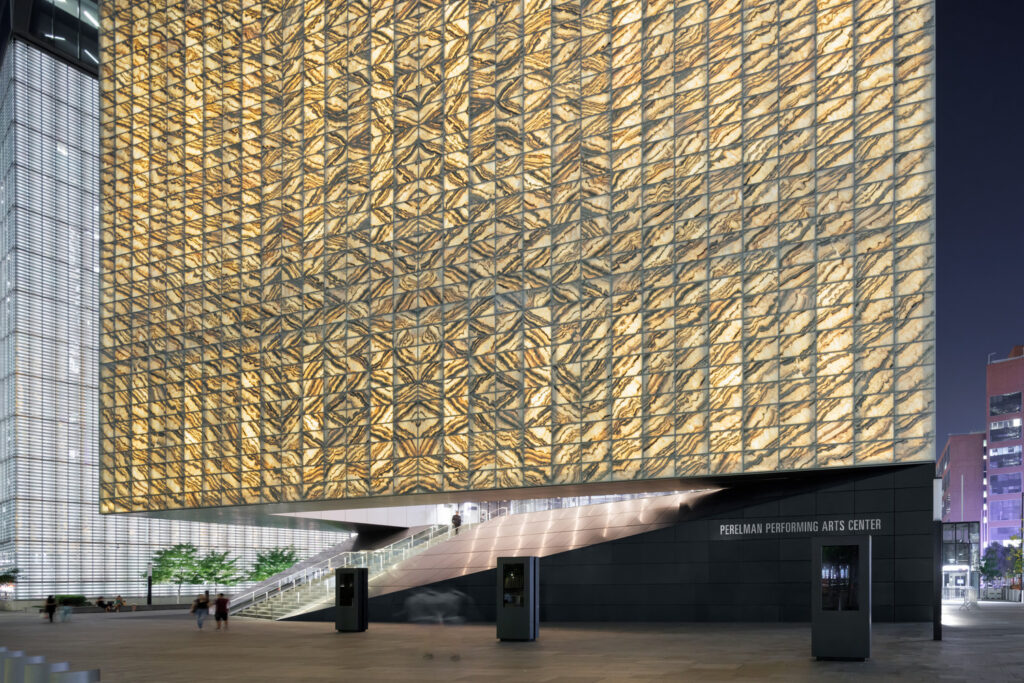 The marble exterior of the Perelman performing Arts Center illuminated at night.