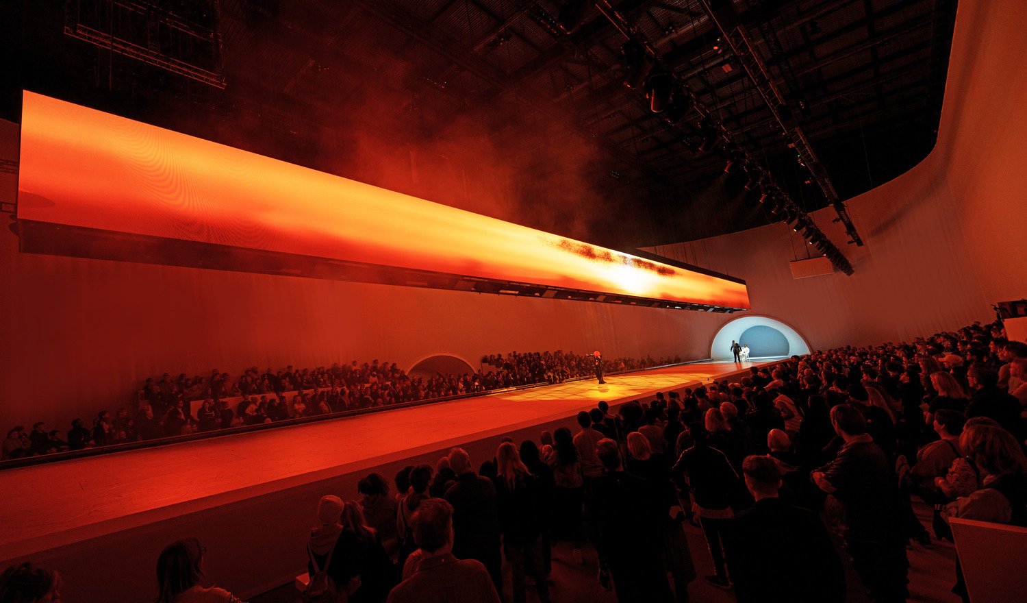 Three performers on stage under fiery light at "Free Your Mind" at Aviva Studios.