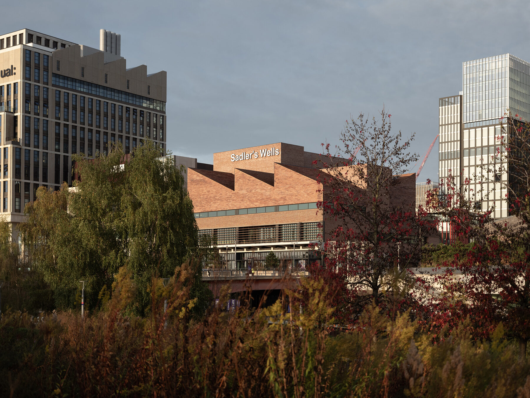The brick exterior Sadler's Wells with jutting triangular roof seen from a distance with intervening trees.