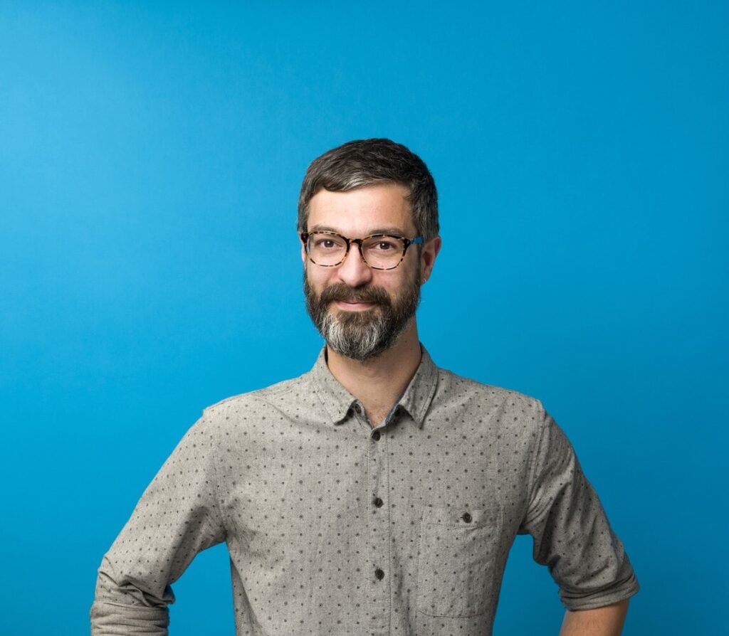 Portrait of Vangelis Koufoudakis on a blue background.