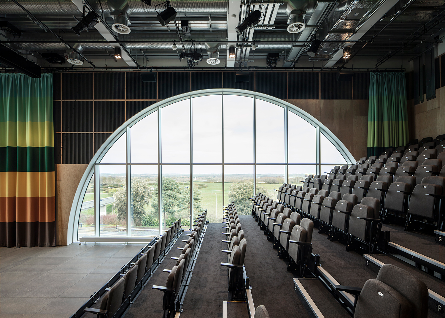 Semi-circular window alongside raised seating area. Colorful curtains and acoustic panels frame the window.