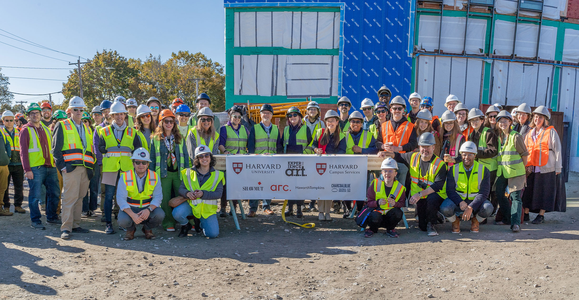 Construction teams pose with Harvard University and American Repertory Theater logos.