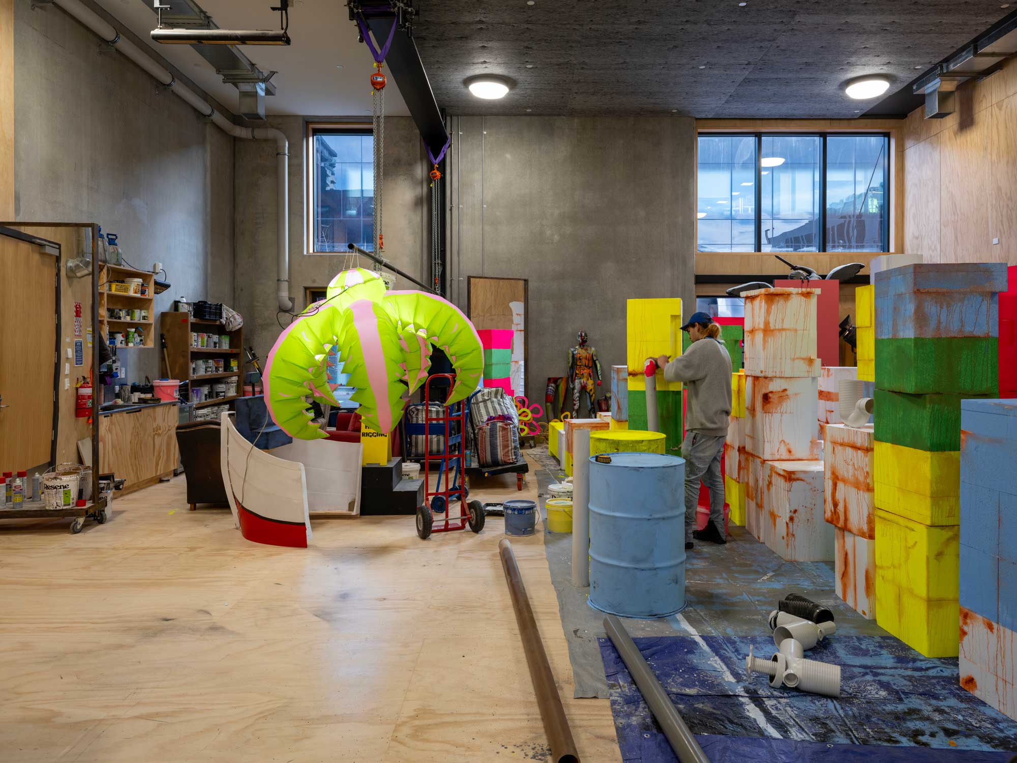 View of colorful, blood-stained boxes, oil drums, and an inflatable lamp in back of house area. © 2025 Simon Devitt Photographer