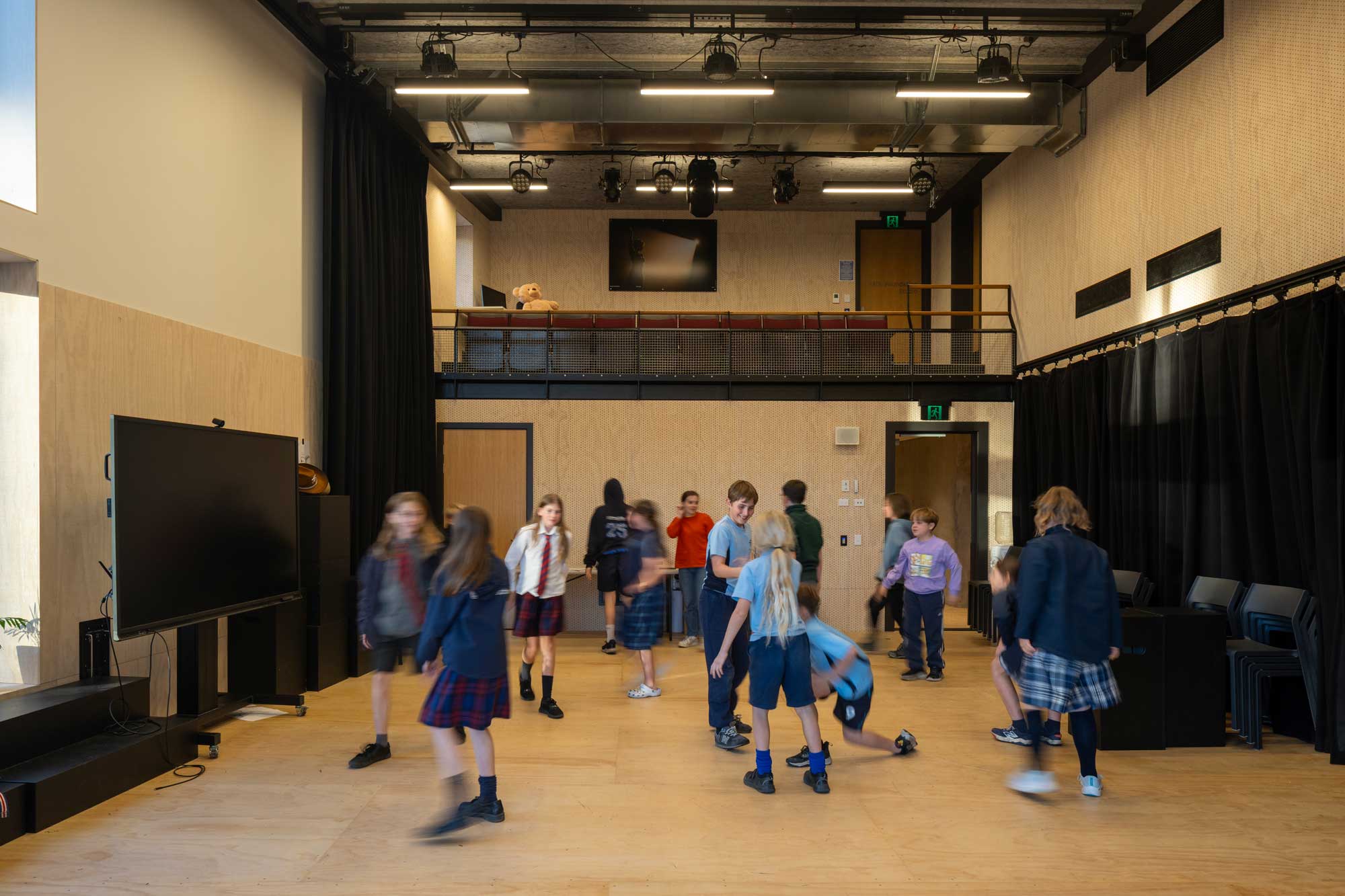 Children in motion in a small room with balcony and black curtains. © 2025 Simon Devitt Photographer