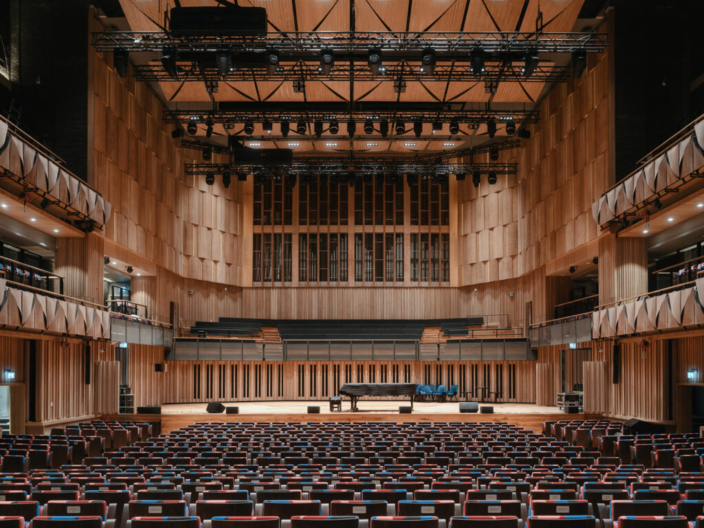 Multicolored seats facing the stage with dimensional wood features lining the walls.