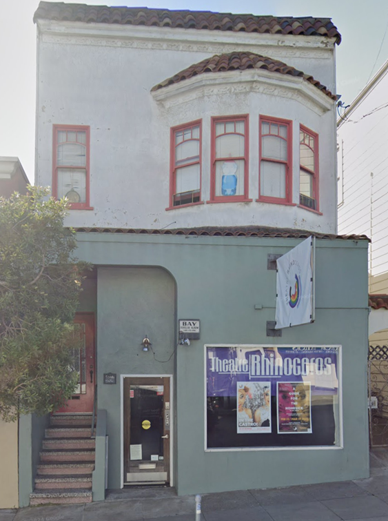 A two-story building seen from the street. The window has a banner that says Theatre Rhinoceros.