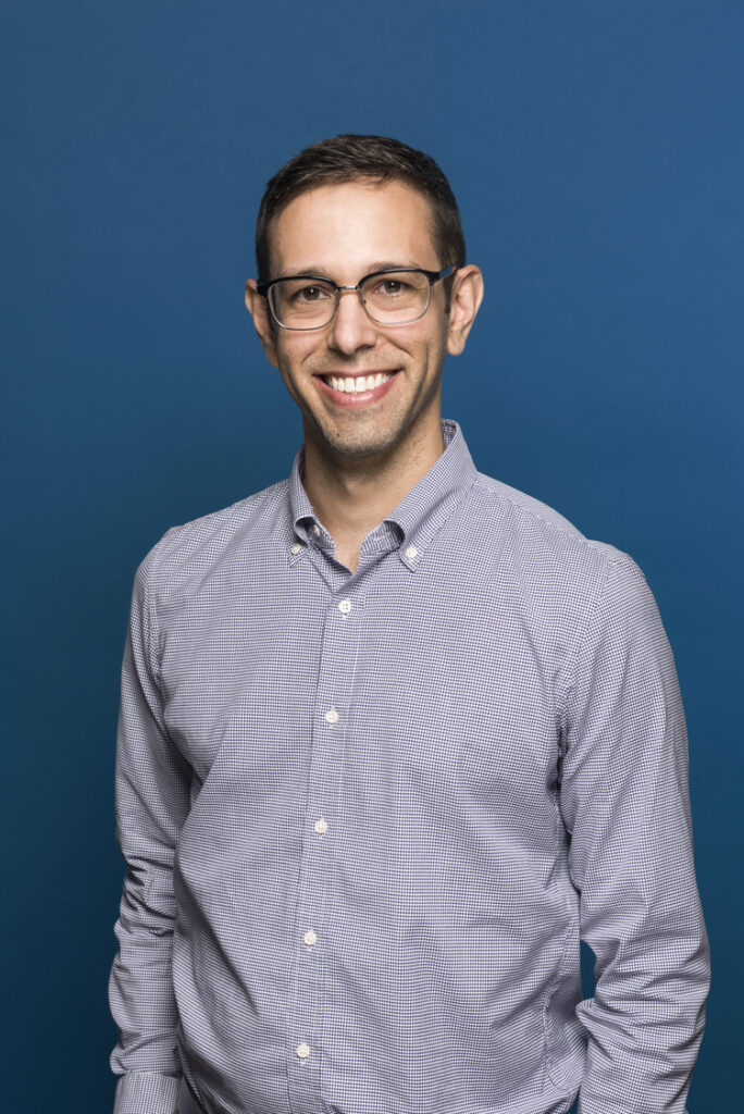 Portrait of Nicholas Correa on blue background.