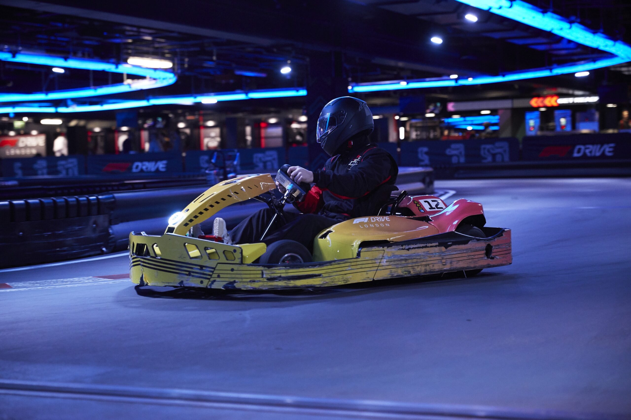 A go-kart driver on the track in a yellow and red car. Photo by Pete Muller.