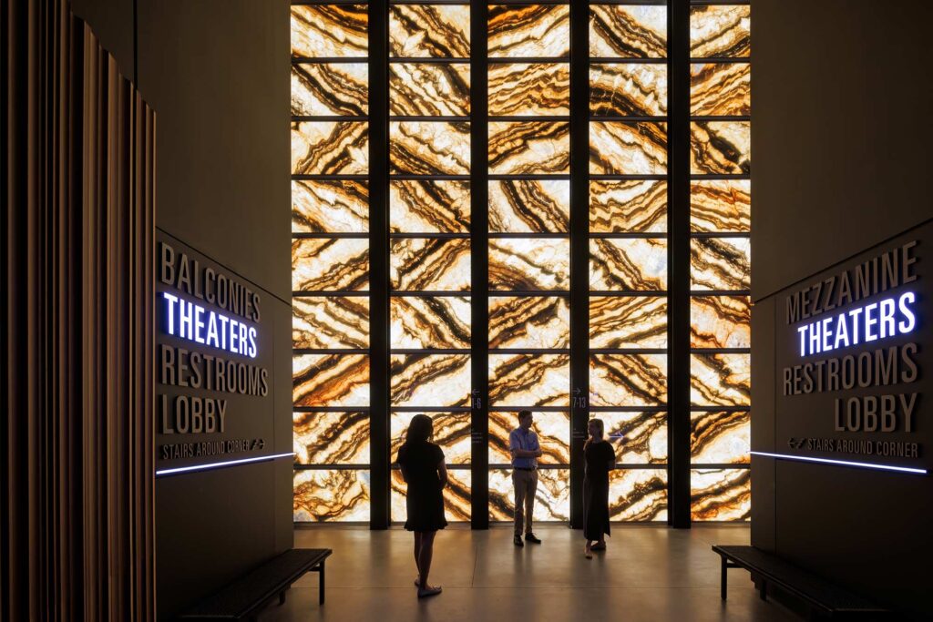 People stand in front of the illuminated marble facade.
