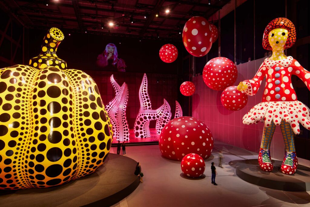 Yayoi Kusama installation "A Bouquet of Love I Saw in the Universe" with giant polka dotted tentacles, pumpkin, spheres, and woman. © David Levene 2023
