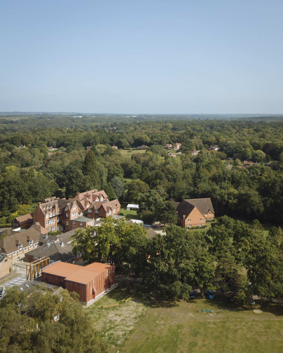 Aerial view of the Horris Hill School campus shows the brick colored theatre building among other brick and gable-roofed buildings.