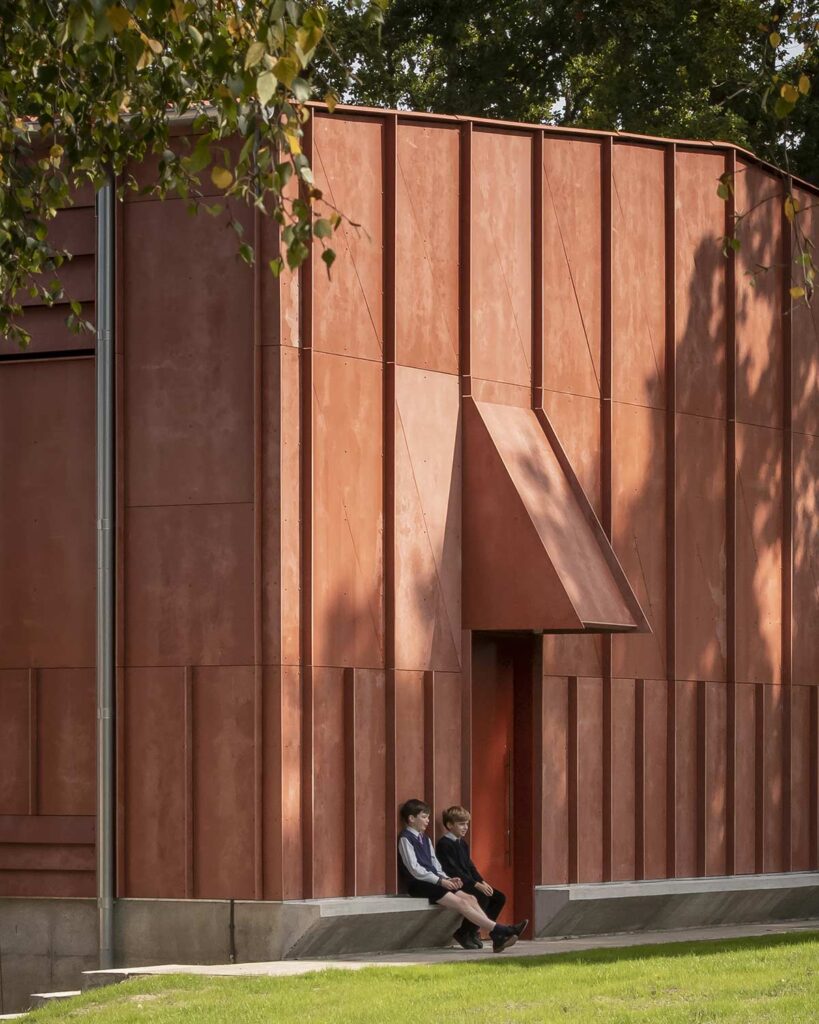 Two boys sit on a concrete ledge bench that protrudes from the base of the building.