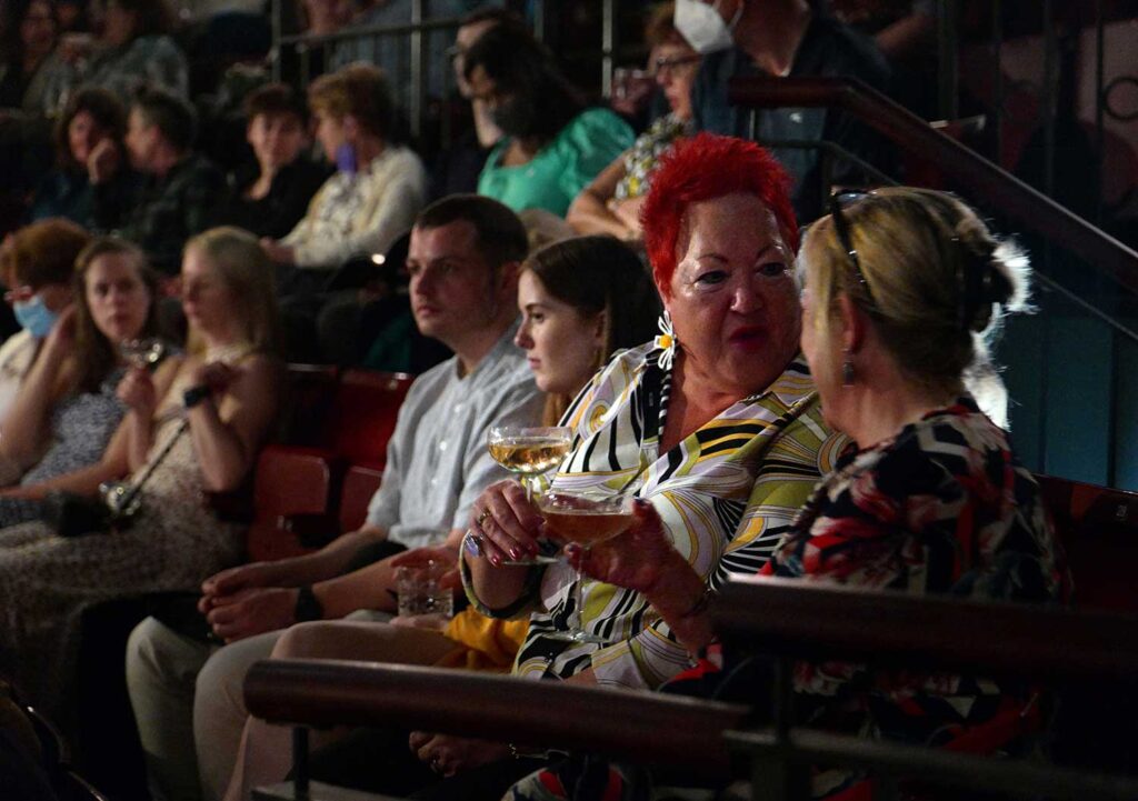 Audience members chat while having drinks.