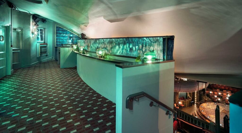 A green balcony area leads down to seating.