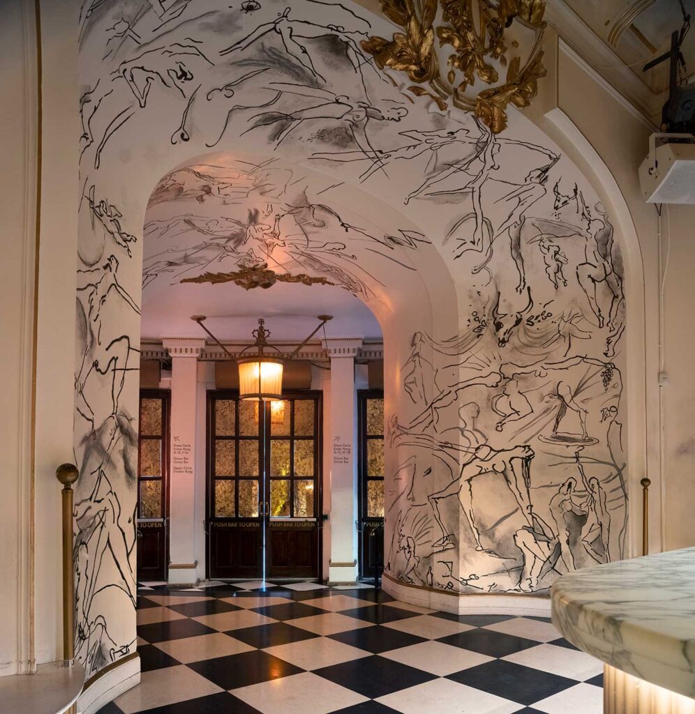 Three sets of double doors with gilded windows peek through a white archway covered in nude ink figure drawings.