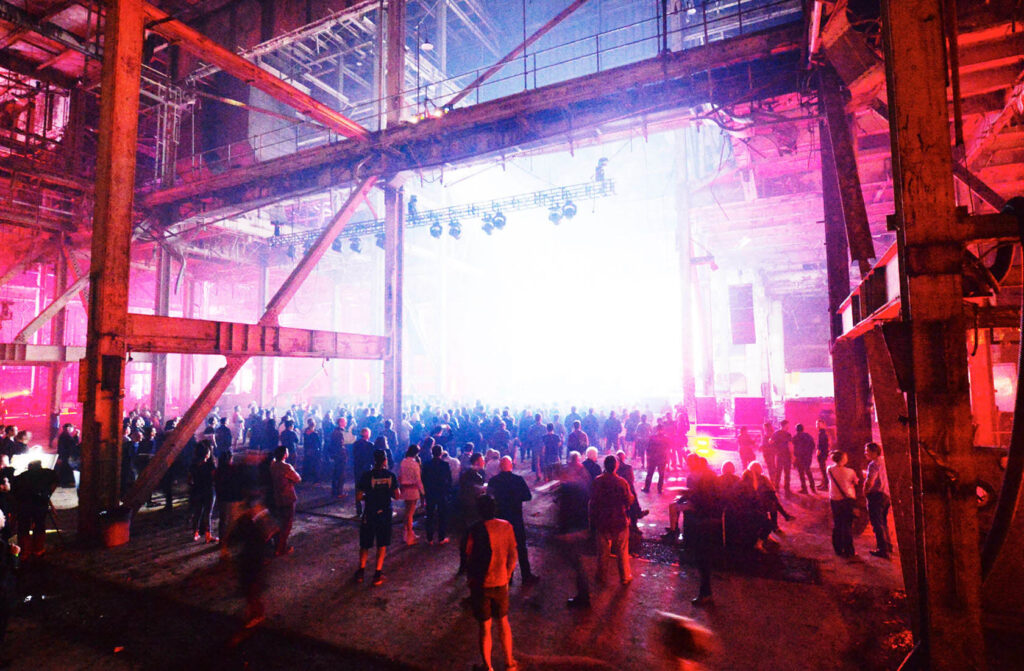 The audience looks at a glowing performance space.