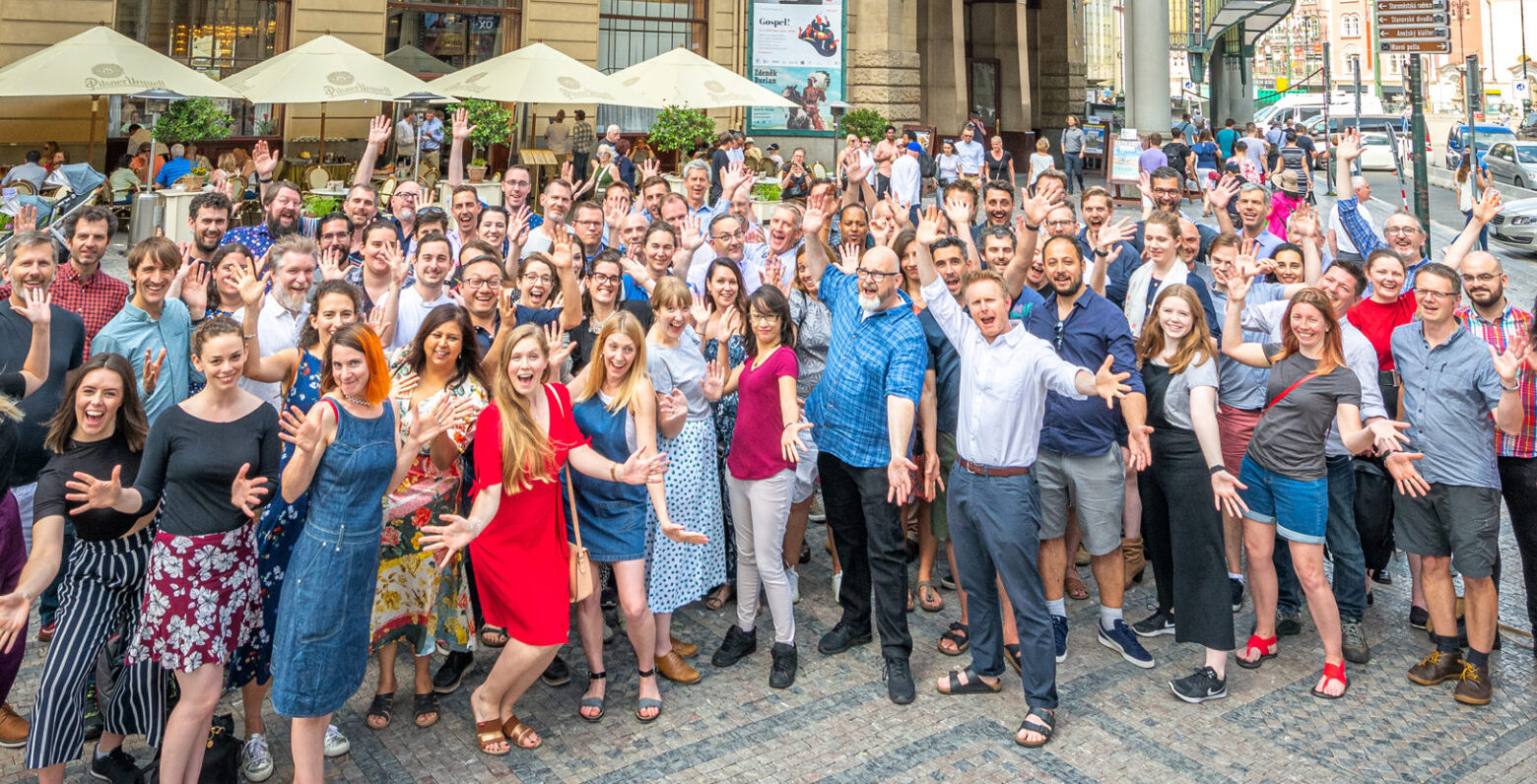 Large group of Charcoalblue staff outside with hands raised.
