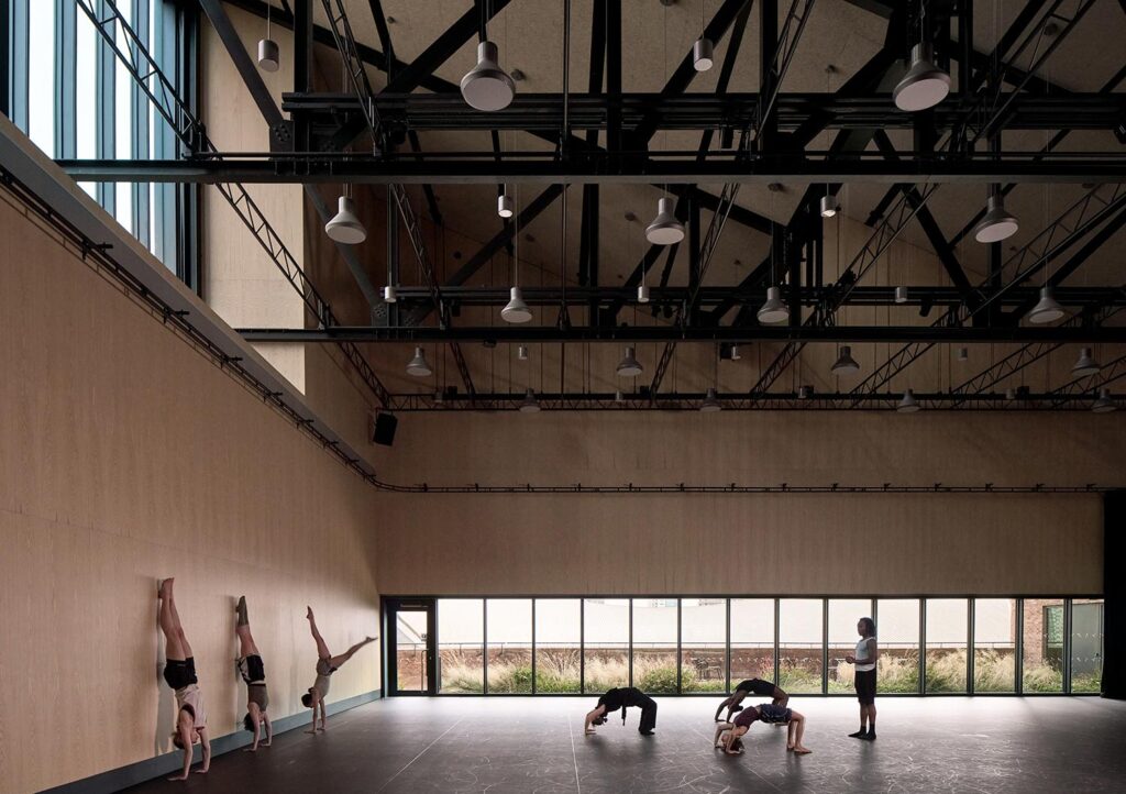 People do handstands against a wall in a studio space. © Nick Guttridge