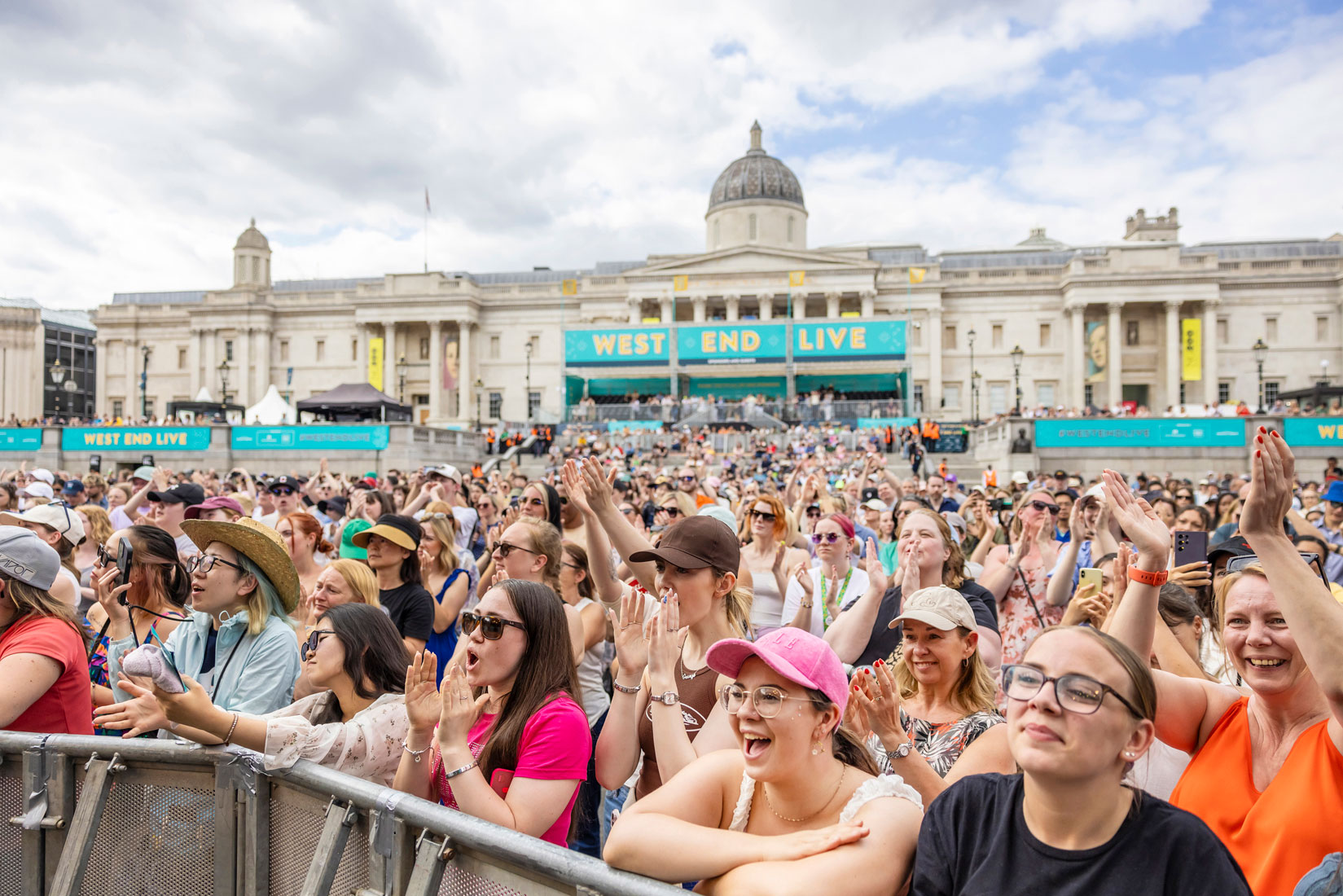 A cheering audience of mostly women raise their hands at West End Live.