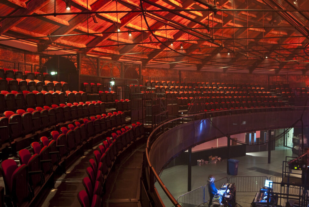 A circular balcony. Below an AV technician works at a table.