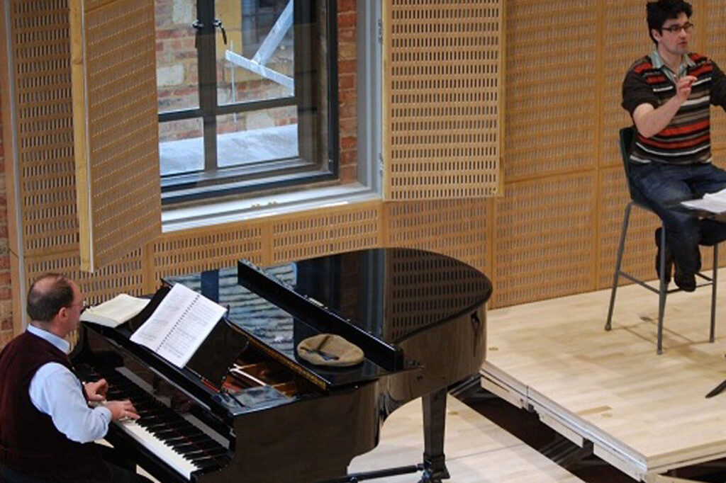 A pianist and a person sitting on an elevated platform.