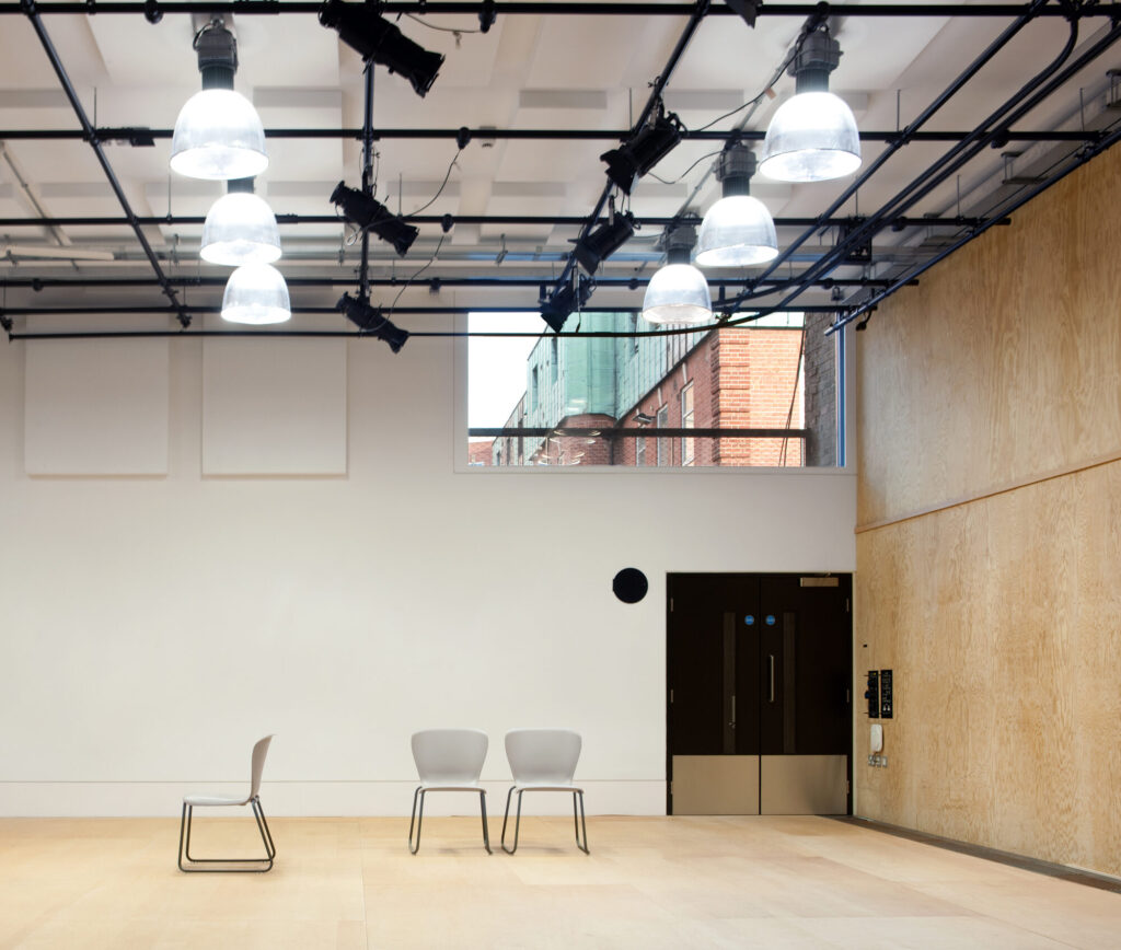 Chairs in a room with bright lights and plywood wall.