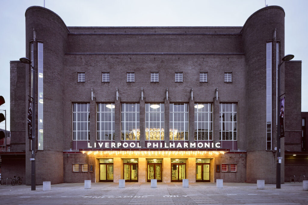 A brick building with round stairwell structure on either end and illuminated sign "Liverpool Philharmonic".