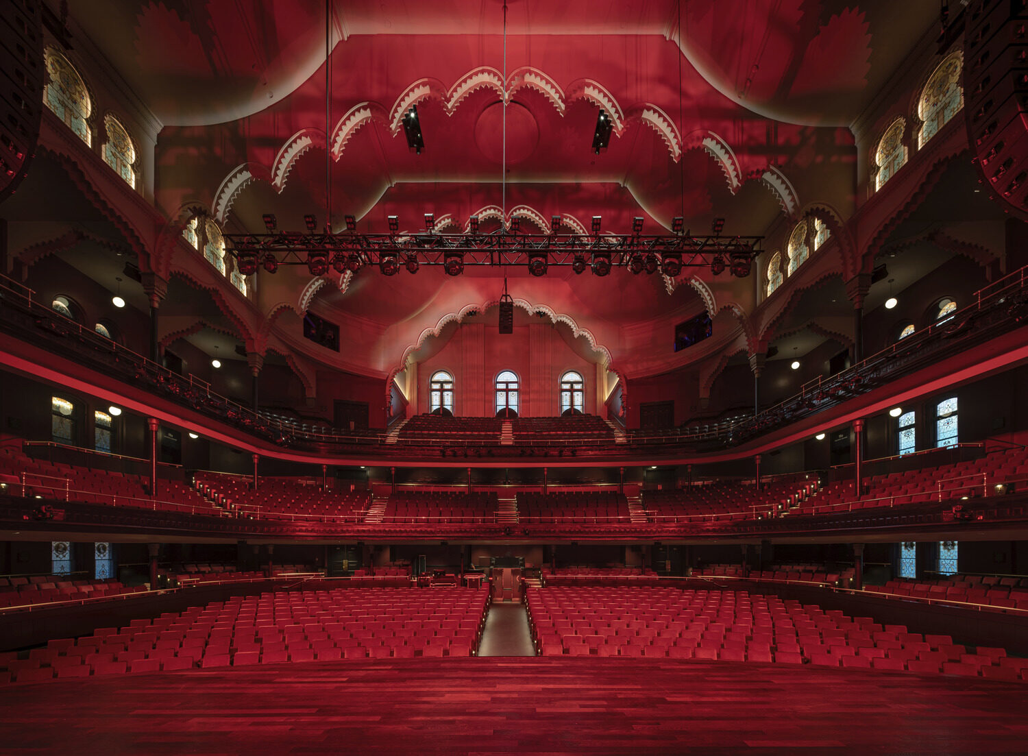 The red hued interior of Massey Hall with scalloped ceiling features.