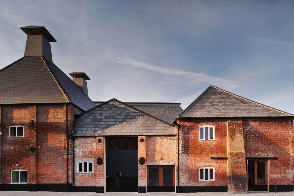 Antique looking brick buildings with irregular angled roof shapes and chimney towers.