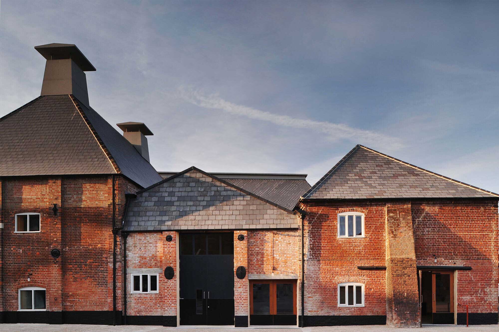 Antique looking brick buildings with irregular angled roof shapes and chimney towers.