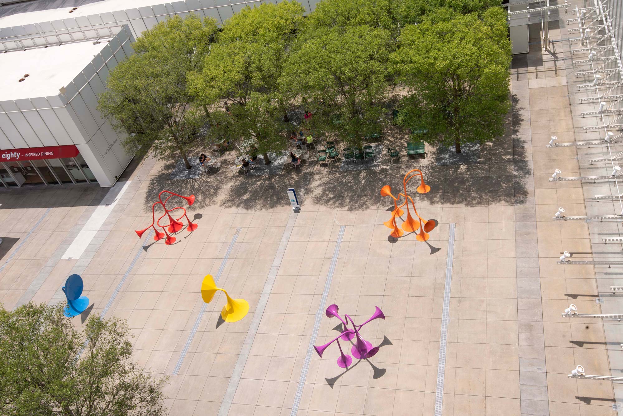 An aerial view of five different colored horn structures in a plaza.