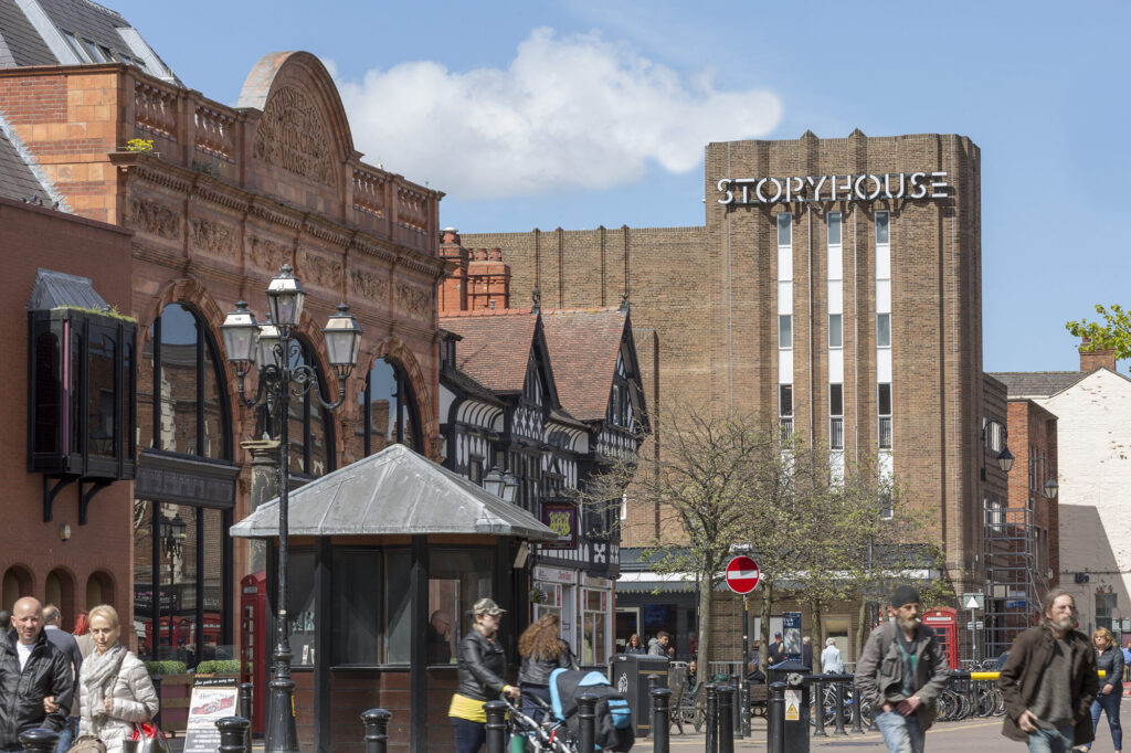 Street view of a tall brick building with a white sign reading "Storyhouse". Photo by Peter Cook