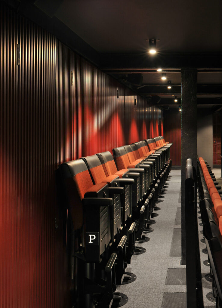 A row of folded seating against a slatted wall.