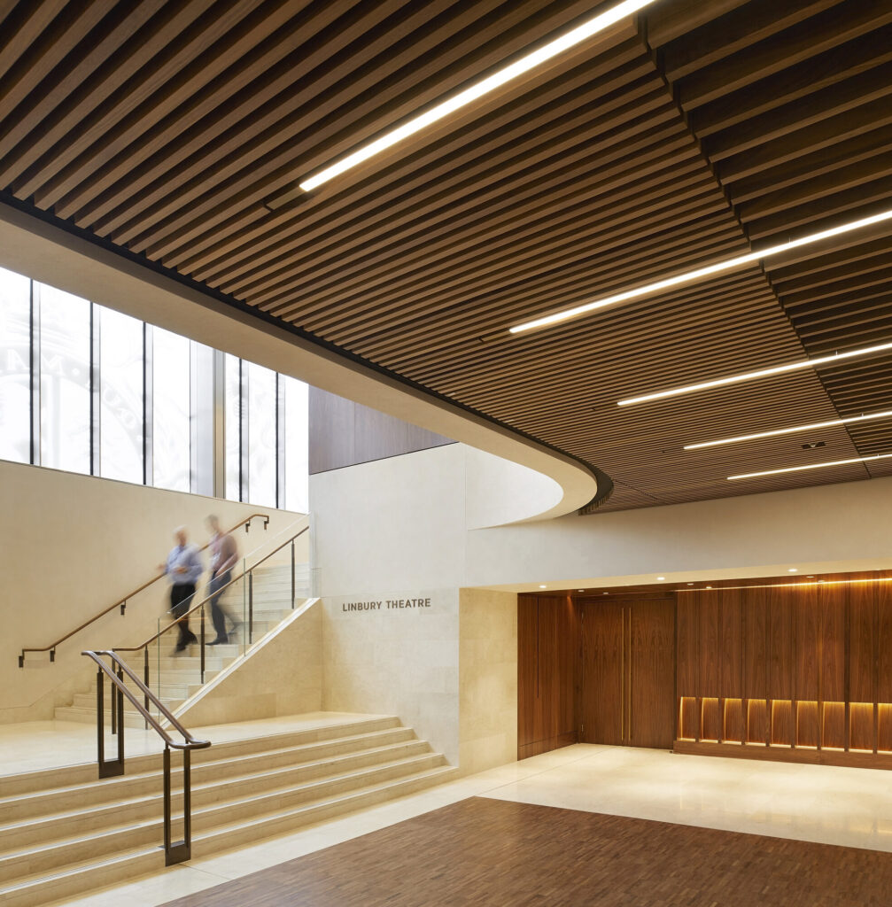 People descend stairs toward the theatre entrance. On the wall a sign reads 