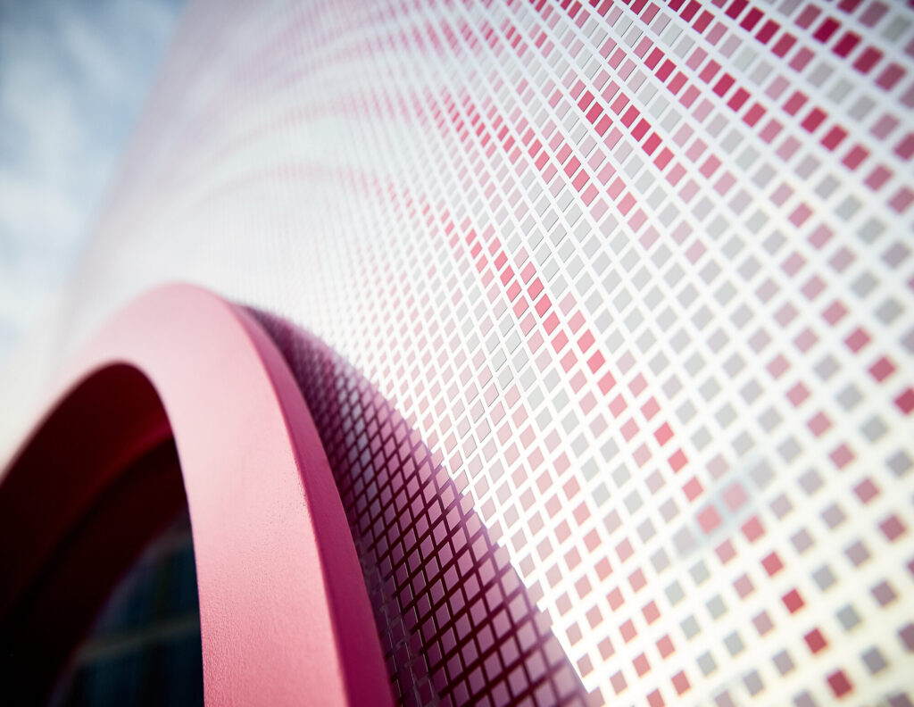 A close up of the reflective surface of the Pod, covered in a mosaic of pink and silver squares.
