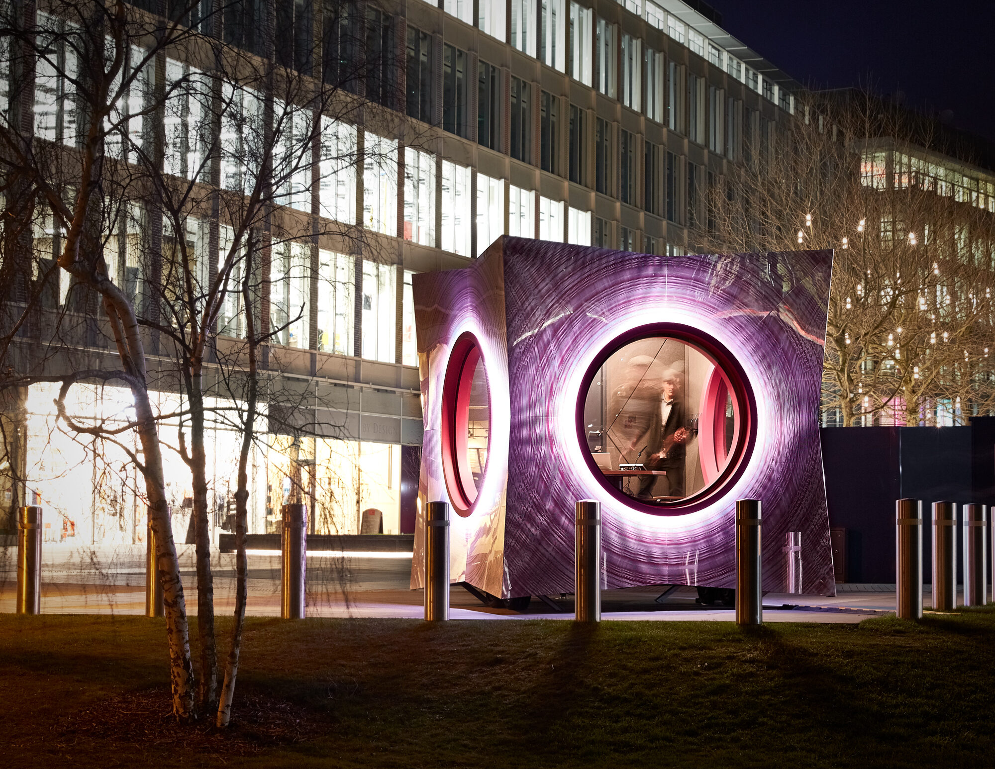 The cube's circular windows are framed with an illuminated halo of light by night.