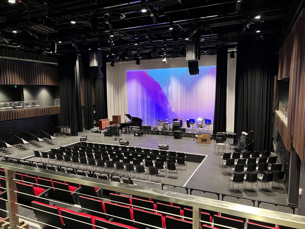 View from balcony level of a contemporary looking stage setup for orchestra use. Image courtesy of Chalk Studio