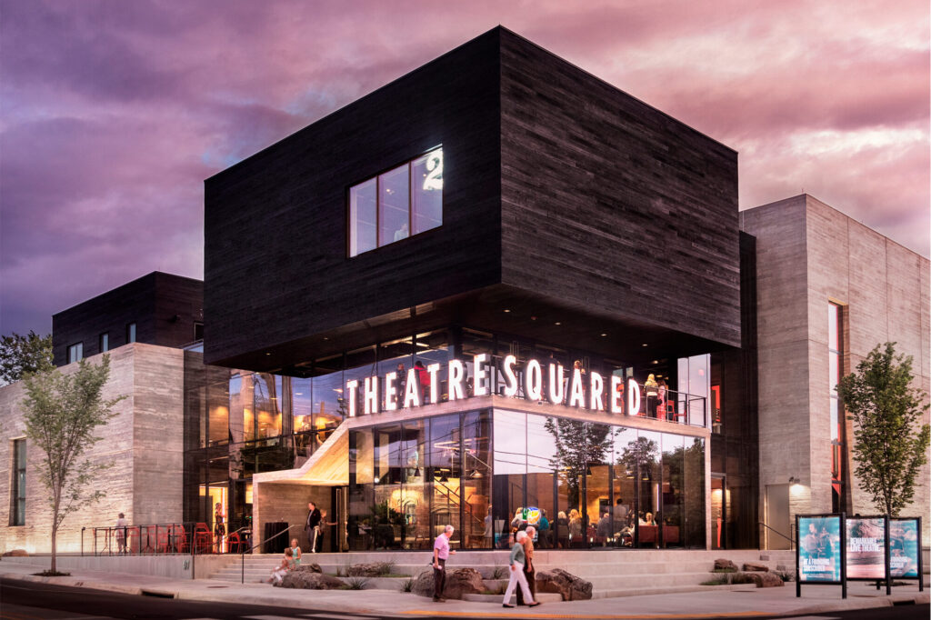 Dark boxy building with with illuminated sign "TheatreSquared".