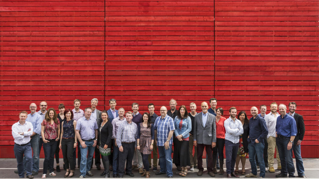 A group of Charcoalblue team members against a red wall.